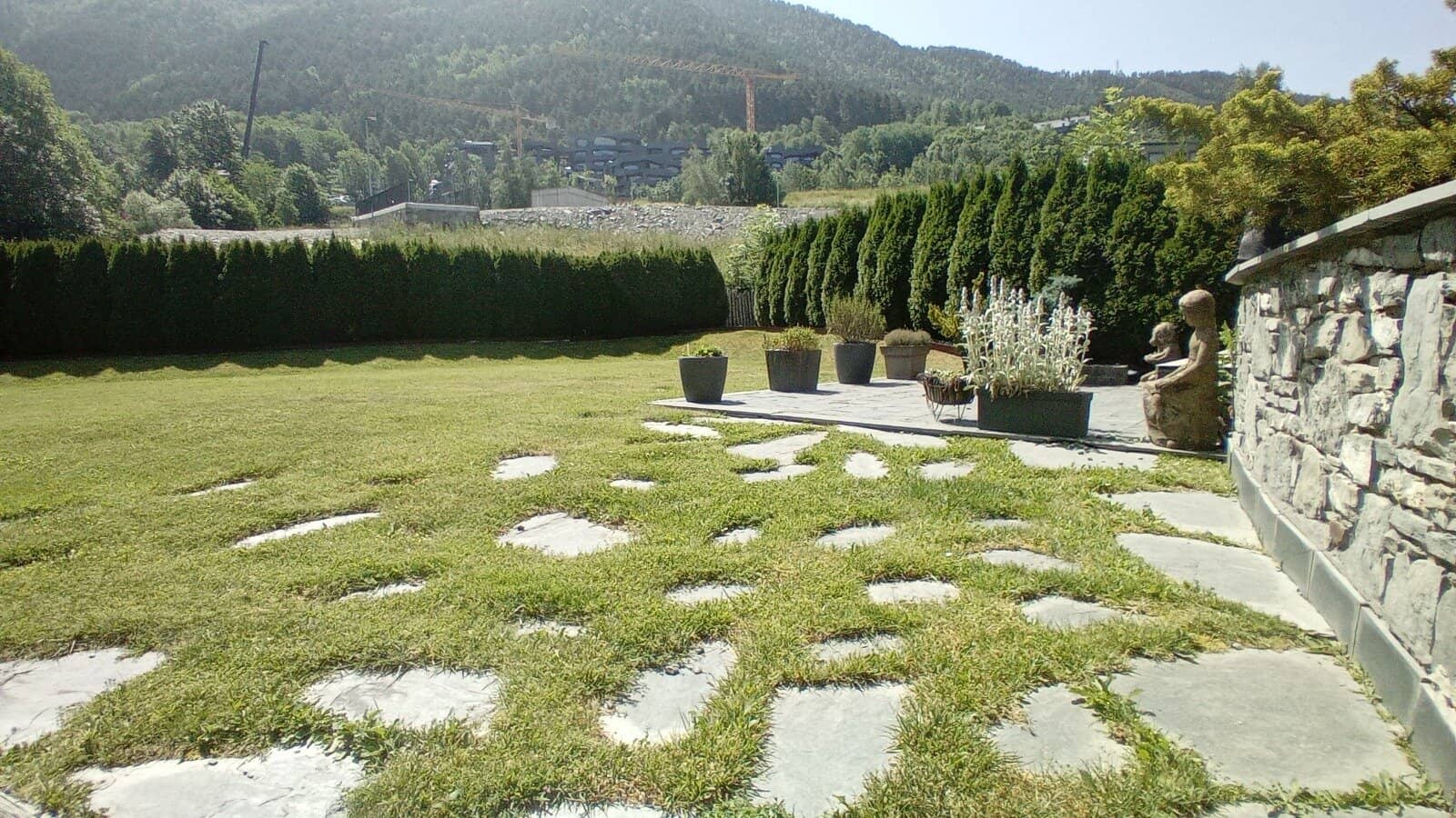 Jardín con césped y macetas en un paisaje de montaña en Andorra.